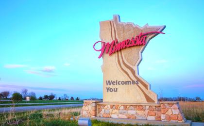 A sign shaped like the state of Minnesota with the phrase "Minnesota Welcomes You" written across it
