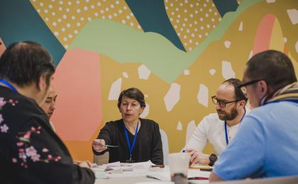 A group of people sitting at a round table discussing together.