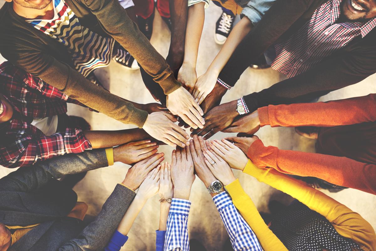 A diverse group of people putting their hands together in the middle of a circle