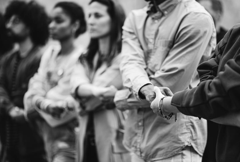A black and white photo of a line of people with linked hands