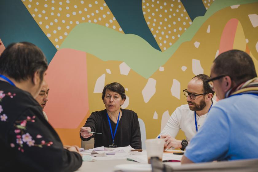 A group of people sitting at a round table discussing together.